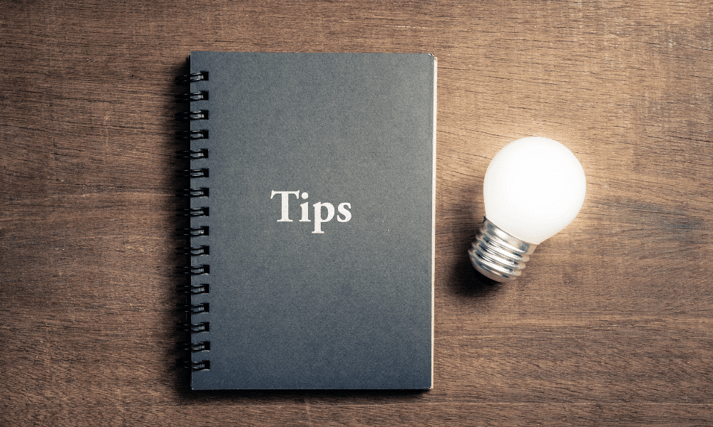 A notebook that says tips on the cover with a lit lightbulb lying beside it