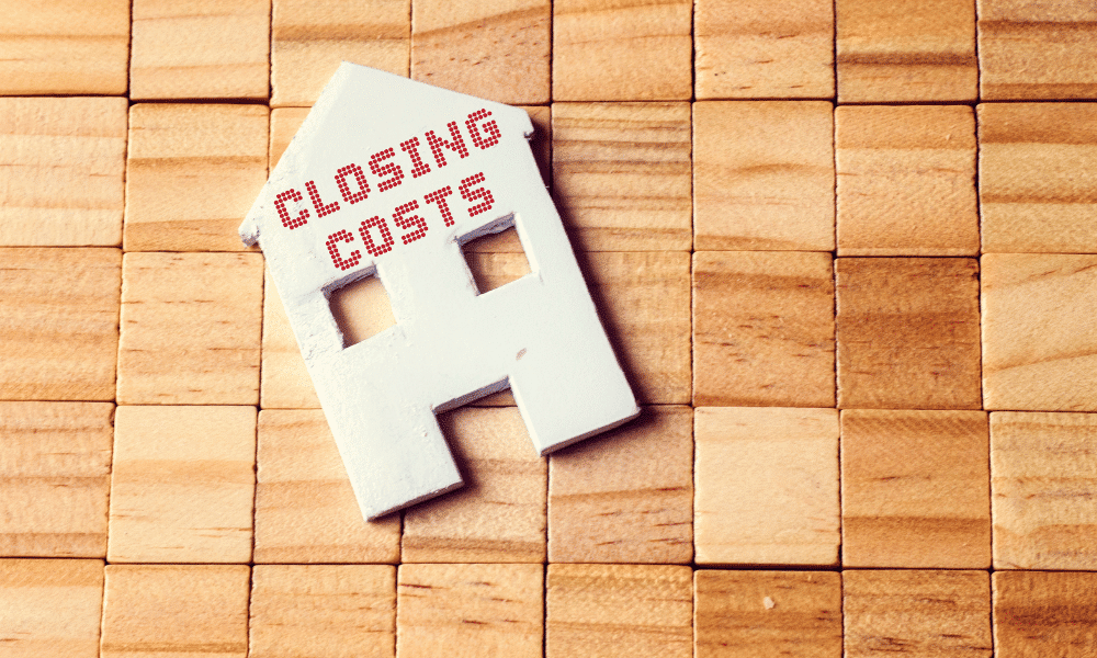 Small wooden blocks with a cutout of a house that says closing costs on it